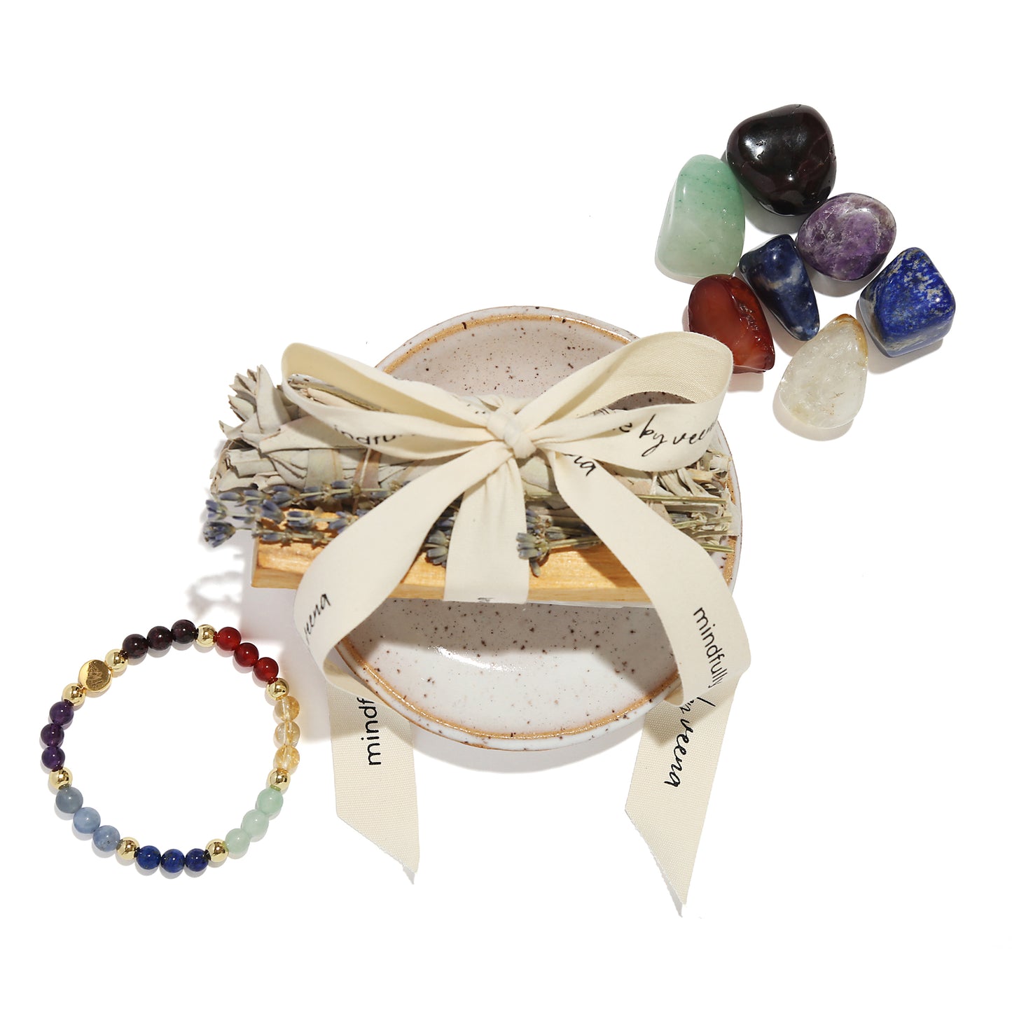 Set of crystals, bracelet, and small bowl with a bow on a white background